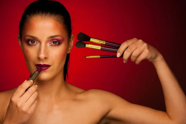 Schöne junge Frau mit Make-up Pinsel über dunklen Hintergrund — Stockfoto