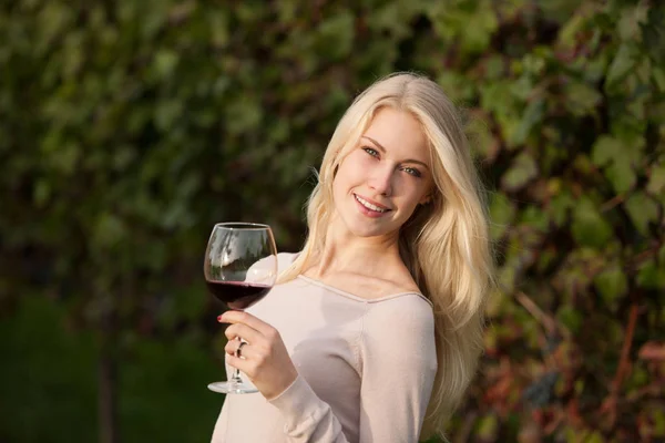 Kvinna dricker rött vin på vingården — Stockfoto