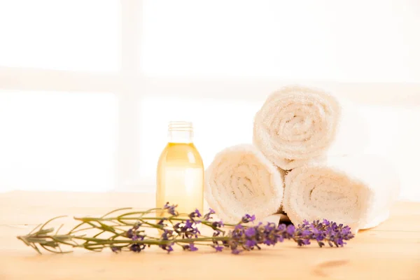 Toallas de lavanda y aceite de masaje en una mesa en el salón de spa —  Fotos de Stock