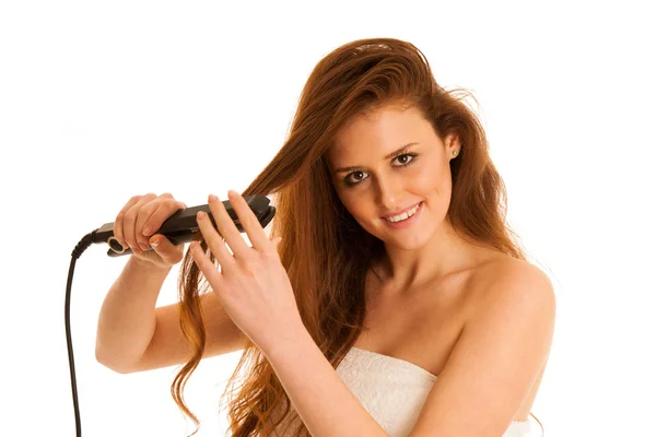 Belle jeune femme aux cheveux longs utilisant des lisseurs de cheveux est — Photo