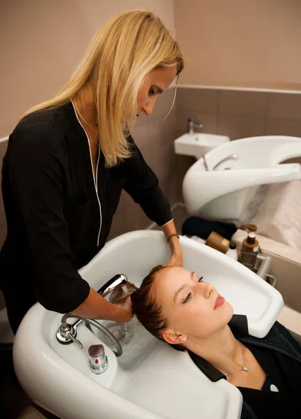 El peluquero en el trabajo - el peluquero que lava los cabellos al cliente — Foto de Stock