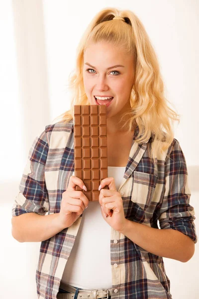 Hermosa mujer rubia se come un gran chocolate — Foto de Stock
