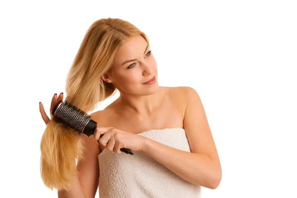 Mulher loira bonita escovando seu cabelo como um sinal og cuidado do cabelo — Fotografia de Stock