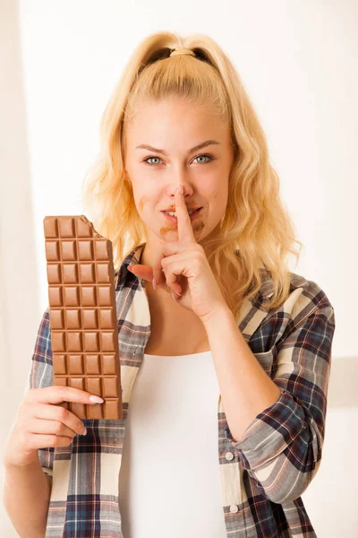 Красивая блондинка ест большой шоколад — стоковое фото