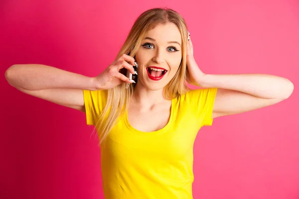 Ενθουσιασμένος ξανθιά εφηβικό κορίτσι μιλάει στο έξυπνο τηλέφωνο πάνω από ροζ bac — Φωτογραφία Αρχείου