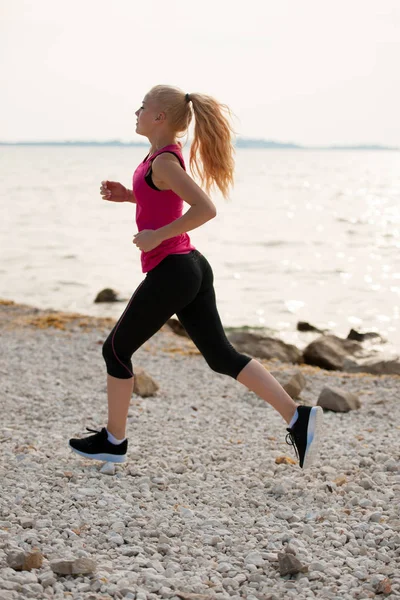 Jogging na praia th - mulher corre perto do mar no início do verão morni — Fotografia de Stock