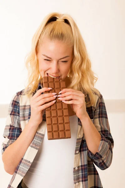 Hermosa mujer rubia se come un gran chocolate — Foto de Stock