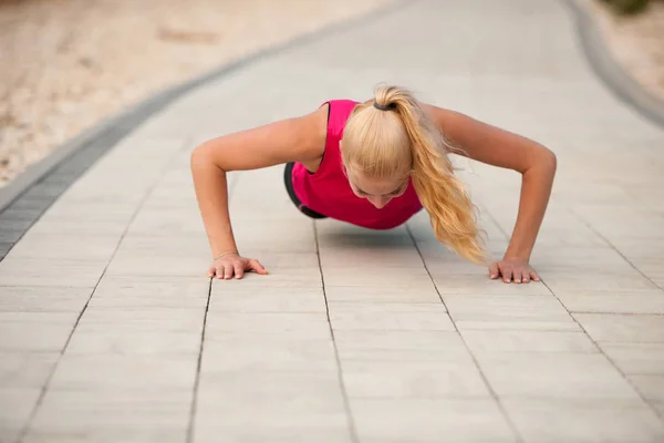 Mujer haciendo flexiones en un camino cerca de un mar —  Fotos de Stock