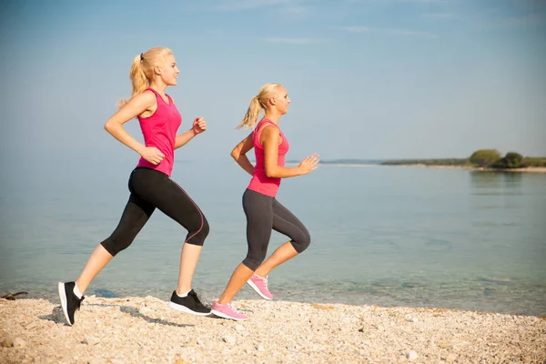 Duas mulheres atletas correndo na praia - início do verão da manhã w — Fotografia de Stock