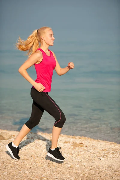 Jogging na praia th - mulher corre perto do mar no início do verão morni — Fotografia de Stock