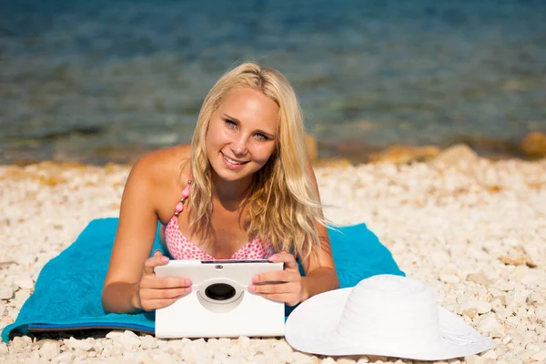 Kvinne som surfer på Internett mens hun ser på nettbrett på stranden – stockfoto