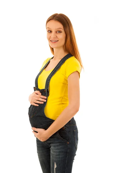 Mujer embarazada en camiseta amarilla y jeans aislados sobre blanco b —  Fotos de Stock