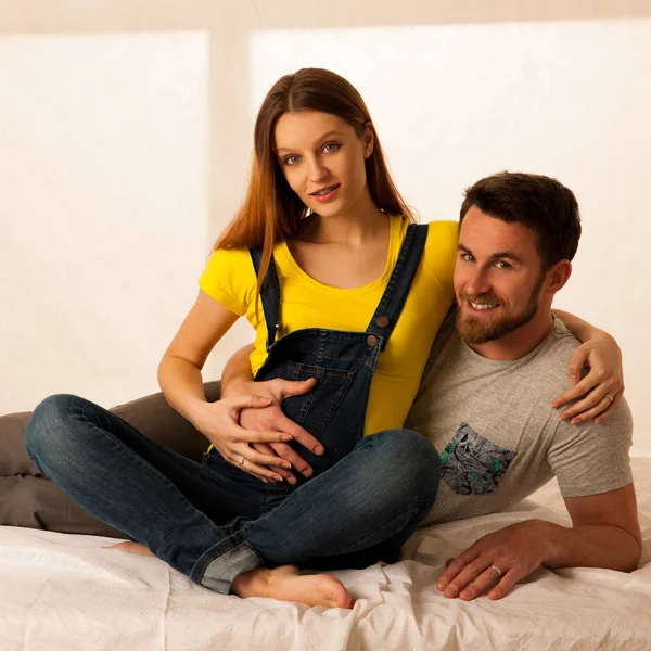 Schöne Coule - junger Mann und schwangere Frau liegen auf dem Bett — Stockfoto