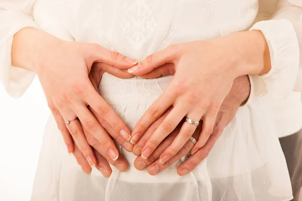 Mężczyzna i kobieta w ciąży, trzymając się za ręce na brzuchu — Zdjęcie stockowe