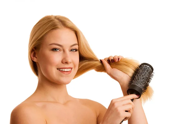 Mulher loira bonita escovando seu cabelo como um sinal og cuidado do cabelo — Fotografia de Stock