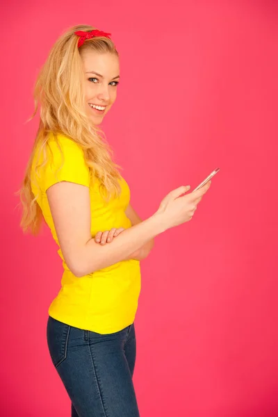 Ung blond tonårstjej i gul t-shirt vid webbsurfning på sm — Stockfoto
