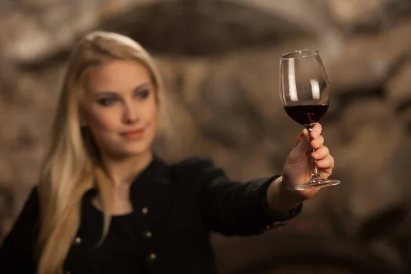 Красивая молодая блондинка пьет вино в винном погребе — стоковое фото