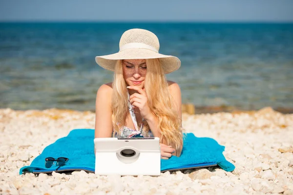 Frau surft im Internet und schaut auf Tablet am Strand — Stockfoto