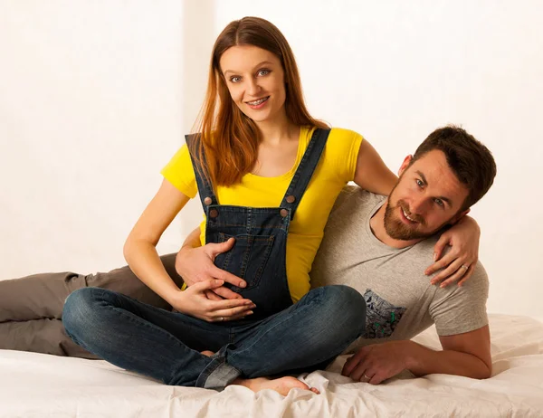 Mooie coule - jonge man en zwangere vrouw rusten op bed — Stockfoto