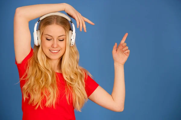 Sarışın genç kadın kulaklık ile müzik bl üzerinde dinler. — Stok fotoğraf
