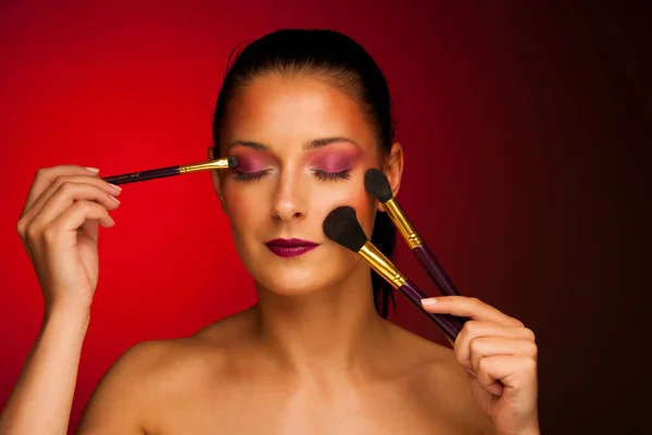 Beauty portrait of a woman with makeup brushes — Stock Photo, Image