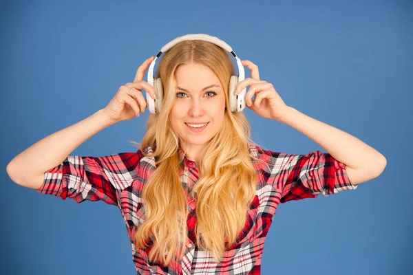 Sarışın genç kadın kulaklık ile müzik bl üzerinde dinler. — Stok fotoğraf