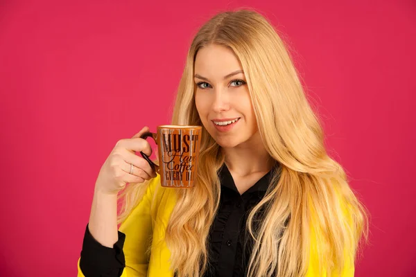 Krásná mladá žena pije káva růžové pozadí — Stock fotografie
