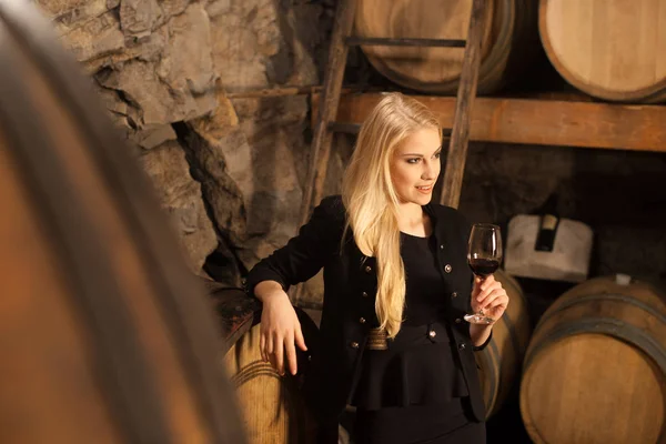 Belle jeune femme blonde boit du vin dans une cave à vin — Photo