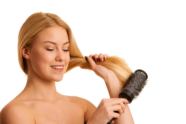 Mulher loira bonita escovando seu cabelo como um sinal og cuidado do cabelo — Fotografia de Stock