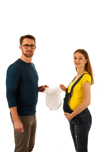 Happy pregnant woman and man holding babys dress isolated over w — Stock Photo, Image