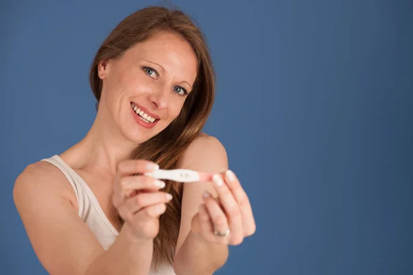 Lycklig kvinna med graviditetstest isolerade över Blå bakgrund — Stockfoto