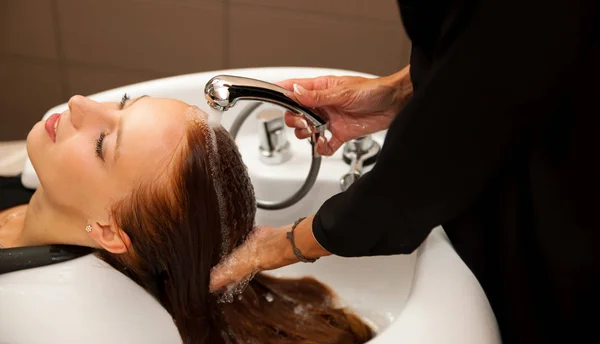 Cabeleireiro no trabalho - cabeleireiro lavando o cabelo ao cliente — Fotografia de Stock