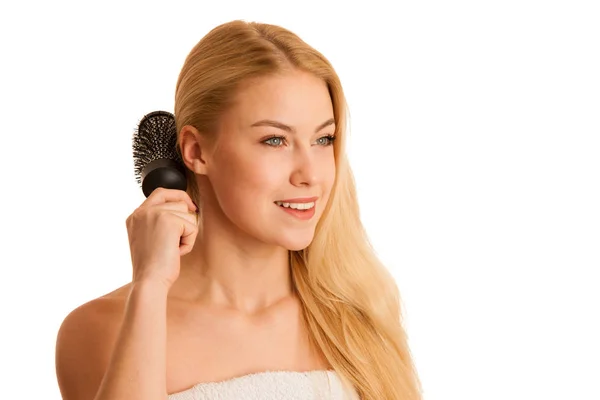 Beautiful blonde woman brushing her hair as a sign og hair care — Stock Photo, Image