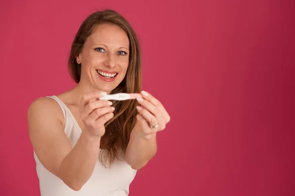 Szczęśliwa kobieta z test ciążowy na białym tle różowy — Zdjęcie stockowe