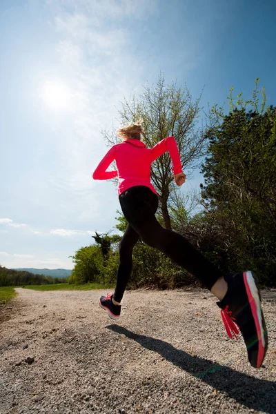 Young woman in pink and black dress runs cross country on a warm — Stock Photo, Image