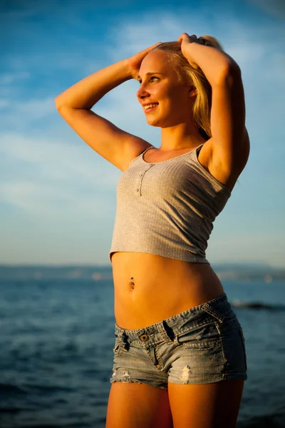 Nuori nainen rannalla auringonlaskun aikaan kuumana kesäpäivänä — kuvapankkivalokuva