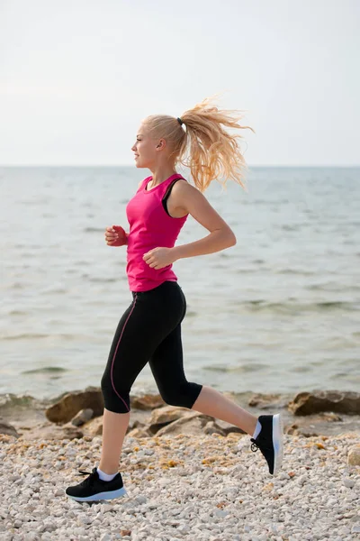 Jogging na praia th - mulher corre perto do mar no início do verão morni — Fotografia de Stock