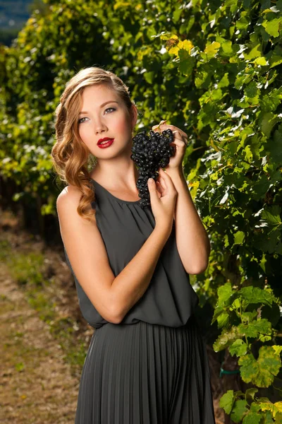 Krásná mladá žena na vinici držící hrozen — Stock fotografie