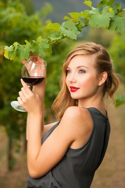Привлекательная стильная женщина пьет бокал красного вина в винограднике — стоковое фото