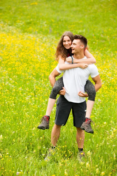 Aktiva lekfulla coupel vandring på en äng i ratly vårgrön g — Stockfoto