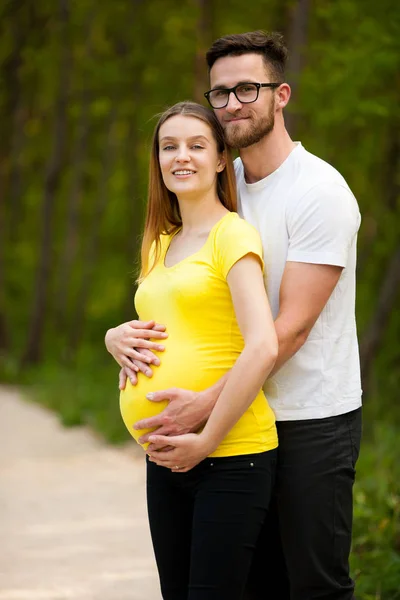 Gravid kvinna med sin man - lyckliga paret i park — Stockfoto