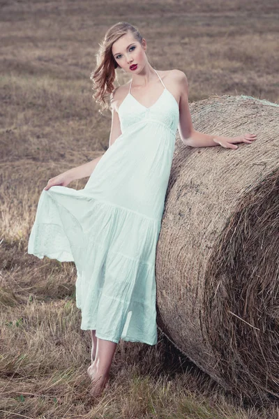 Attractive stylish Woman in  long white summe dress near hay bal — Stock Photo, Image