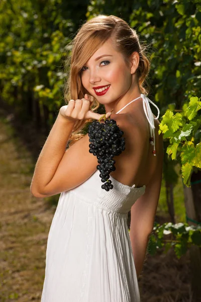 Schöne junge Frau im Weinberg mit einer Weintraube — Stockfoto