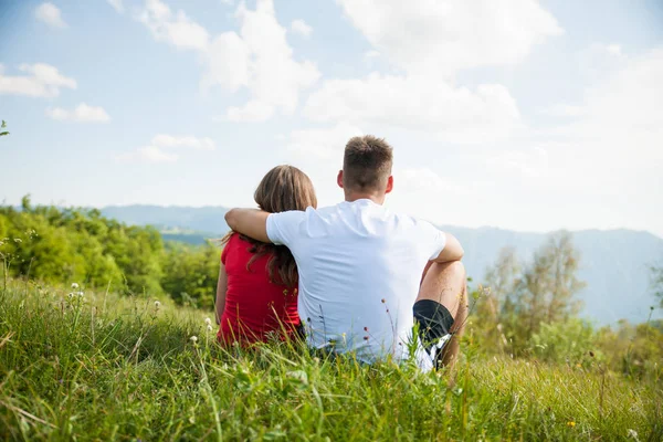 Active couple rests on a mountain peak looking on a mountain lan — Stock Photo, Image