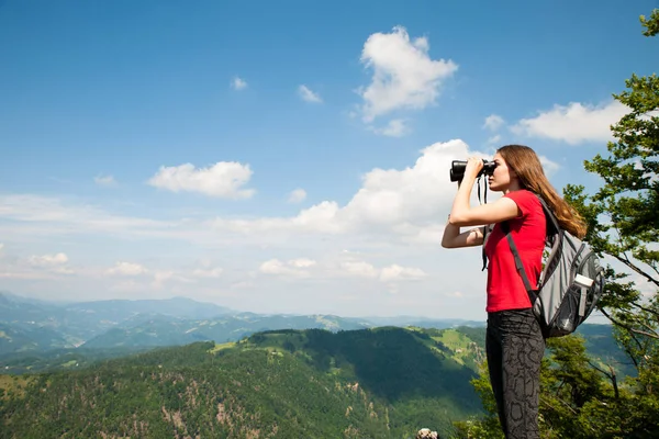 Jovem ativo olhando uma paisagem de montanha com binóculos — Fotografia de Stock