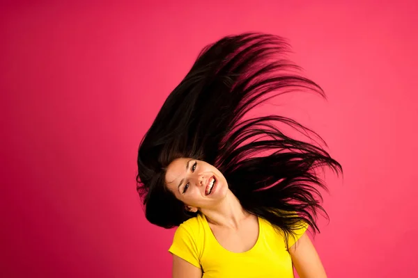 Atractiva joven escucha música sobre fondo rosa — Foto de Stock