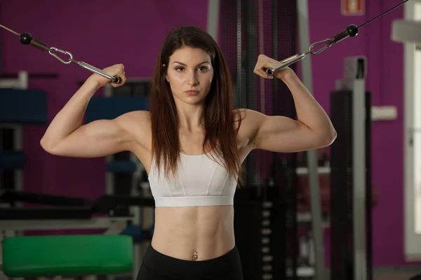 Actove genç kadın egzersiz fitness onun kollarında club spor salonu — Stok fotoğraf