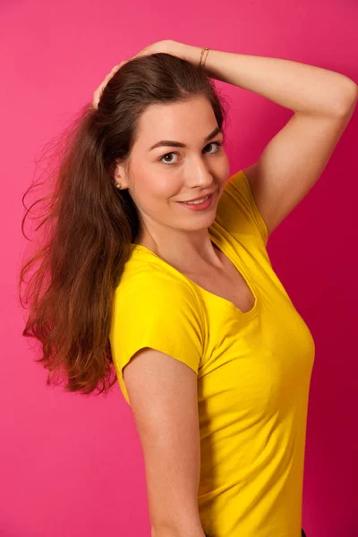 Attractive young woman in yellow t shirt over vibrant pink backg — Stock Photo, Image