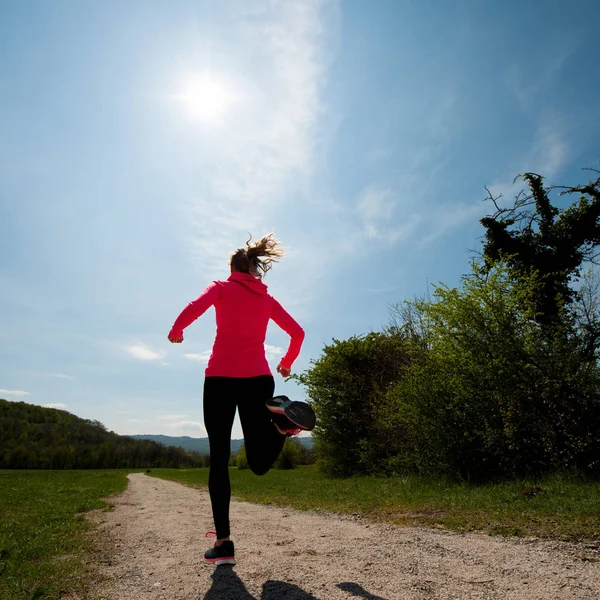 Young woman in pink and black dress runs cross country on a warm — Stock Photo, Image