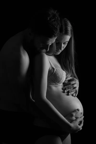 Беременная женщина и ее мужчина студия черно-белой фотографии — стоковое фото